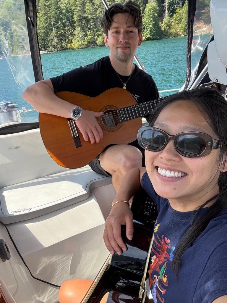 Charles Boddie and Bianca Chan playing guitar on their sailboat